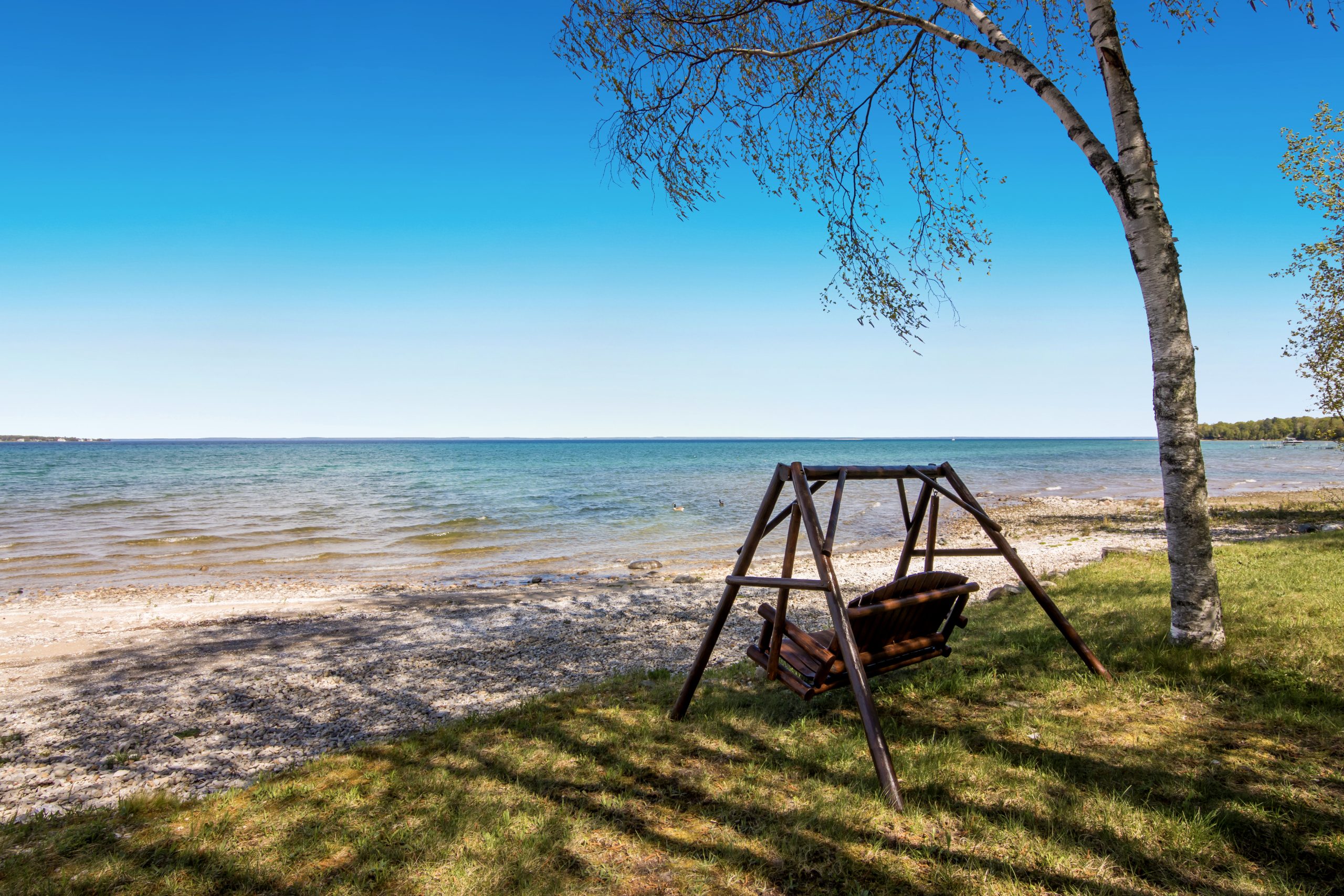 Sandy and pebbly shoreline with clear shallow water along the lake