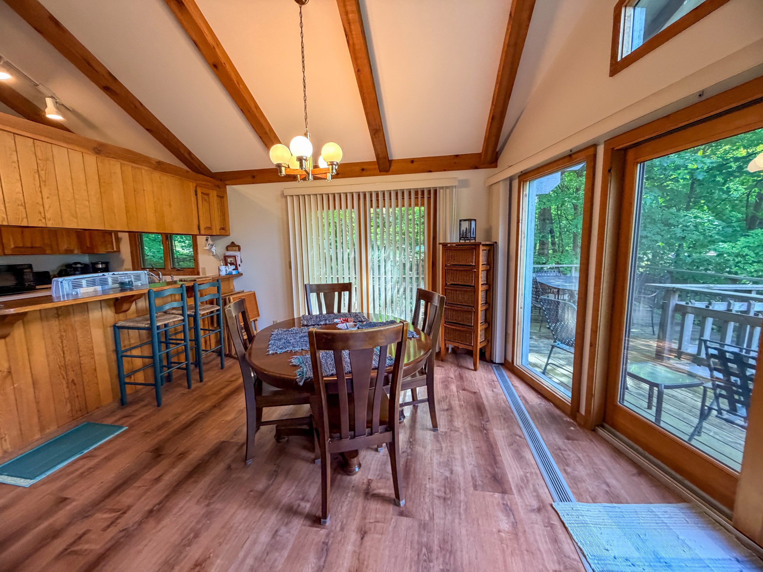 Dining table and kitchen beside glass doors with a view of the trees at Empire Escape