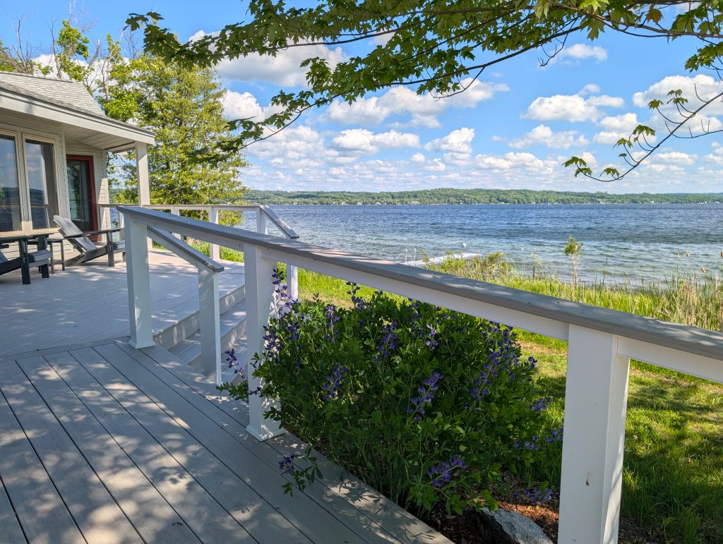 Porch railing and steps with lake water and sky in the distance at Leelanau Lakeshore Lodge
