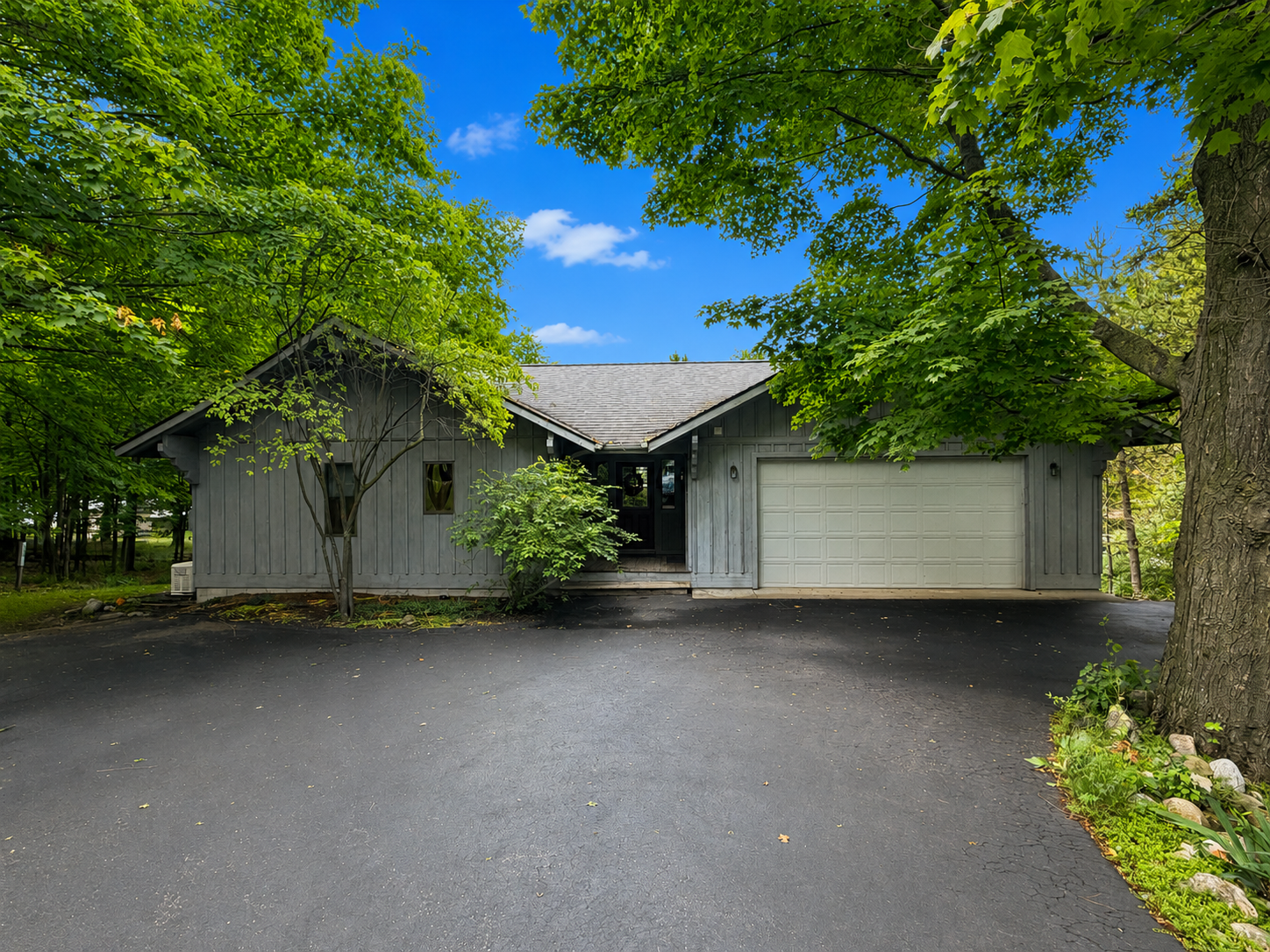 Angled view of Empire Escape's garage front, driveway and mature trees in Empire, Michigan