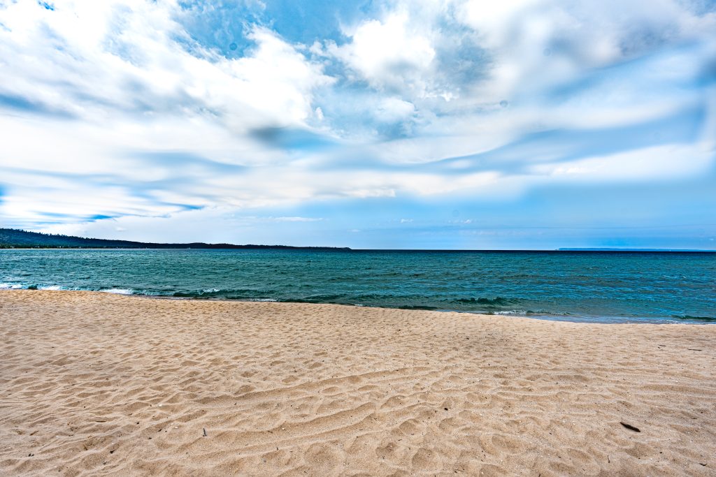 Flat sandy beach meeting turquoise water beneath a cloudy sky near Glen Arbor, Michigan